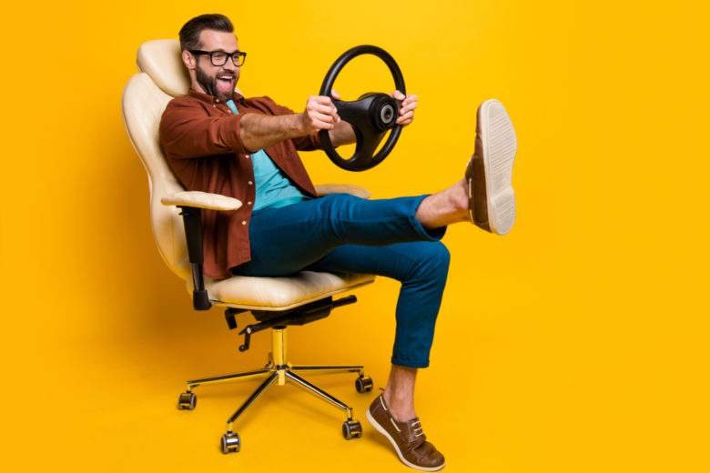 A man on a yellow armchair with a steering wheel in his hand