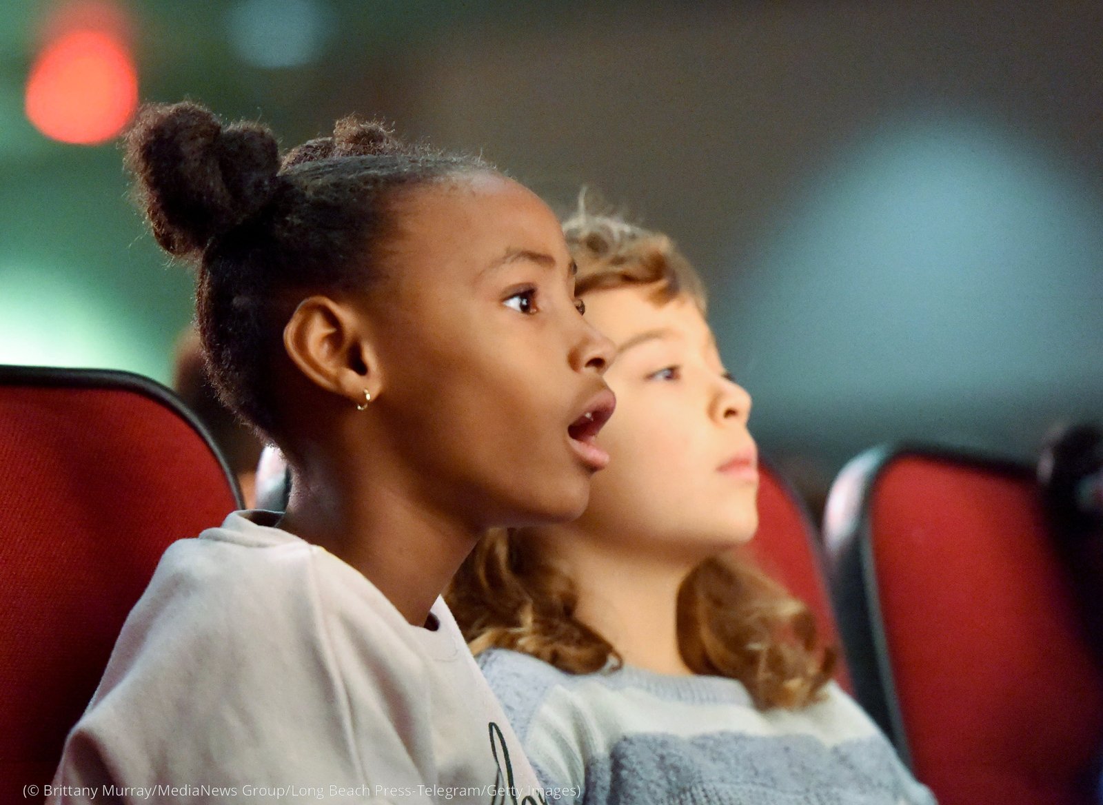 Two girls sit in a theater and look ahead (© Brittany Murray/MediaNews Group/Long Beach Press-Telegram/Getty Images)