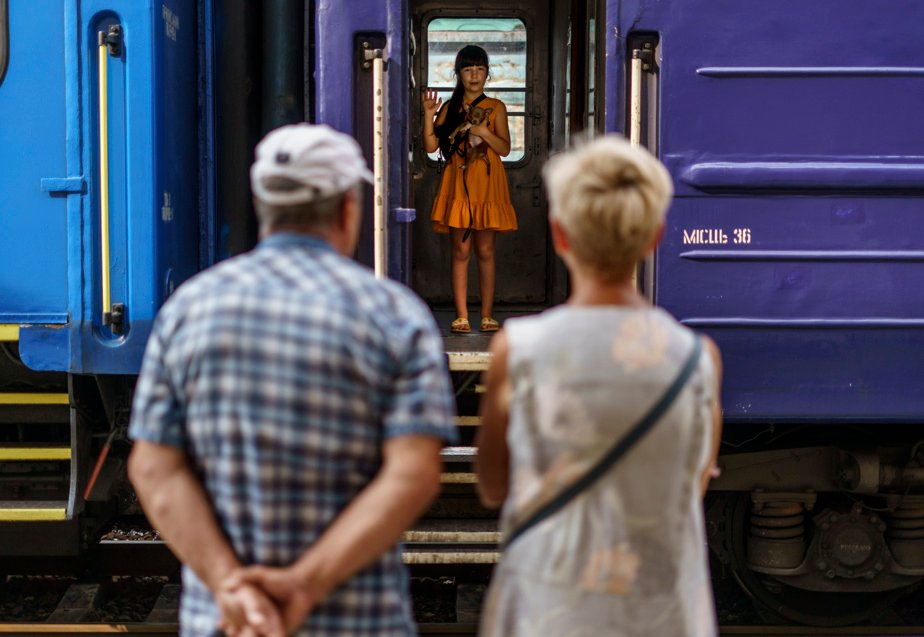 A young girl holds her dog as she greets her grandparents from an evacuation train leaving Pokrovsk, Donetsk region, on August 2, 2022.
