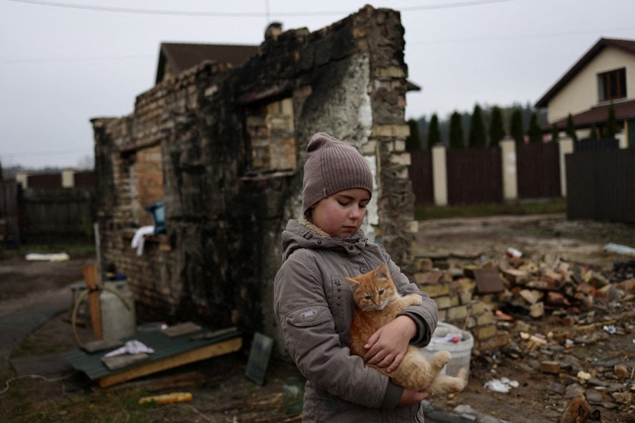 Yuliia Zaika, a 9-year-old Ukrainian girl, holds her cat Marsyk in front of her half-sister's destroyed house in the village of Moshchun near Kiev on November 8, 2022.