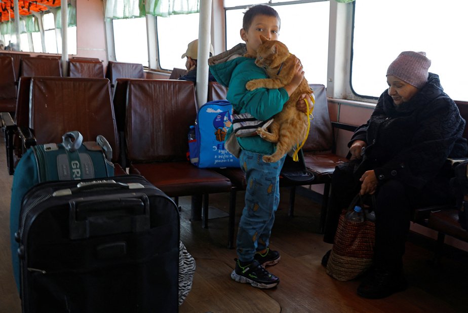 A boy holds a cat aboard a ferry during the evacuation of residents of Kherson on October 31, 2022.