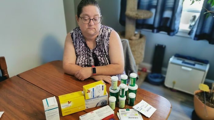 Susan Judges sits at a table with medicine on it.